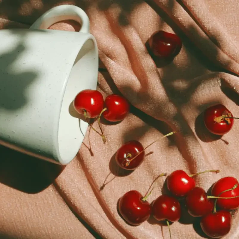 Cup of cherries on a pink cloth