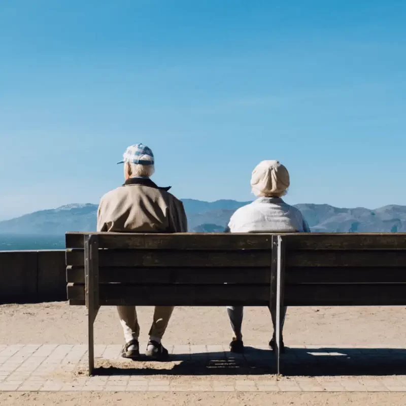 Couple of people sitting on top of a wooden bench