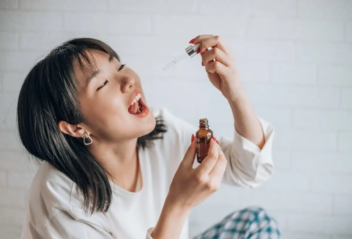 young woman taking cannabis tincture