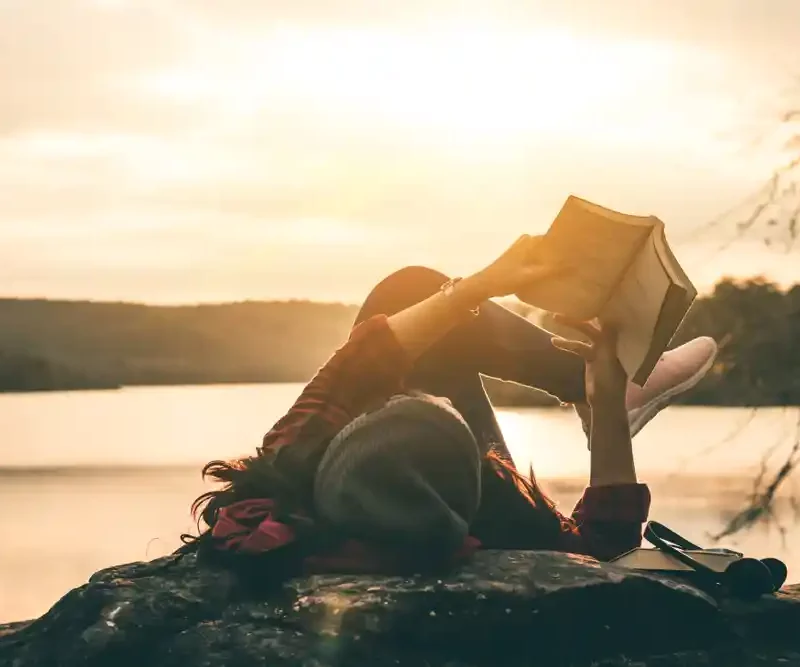 Girl reading a book in a sunset