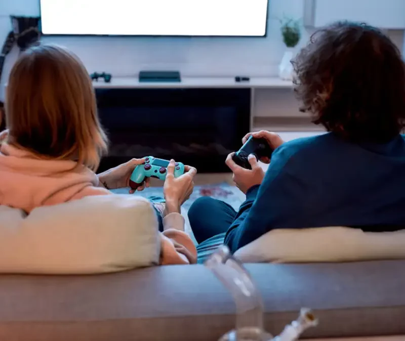 Two people sitting on a couch playing a video game