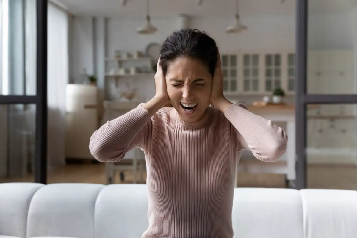Anxious young hispanic woman shout stop cover ears with palms unable to hear loud music noisy sound