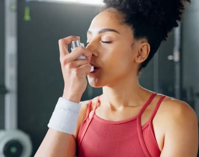 Asthma inhaler breathe at gym with fitness coach for chest relief and wellness