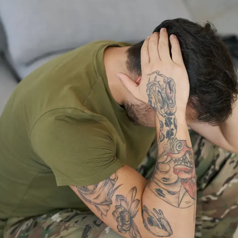 Man sitting on the floor covering his face with his hands