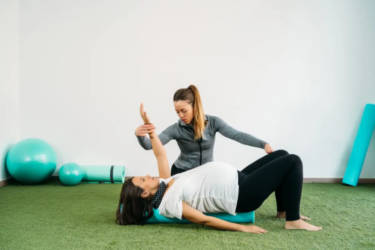 Pregnant woman doing fitness ball and pilates exercise with coach