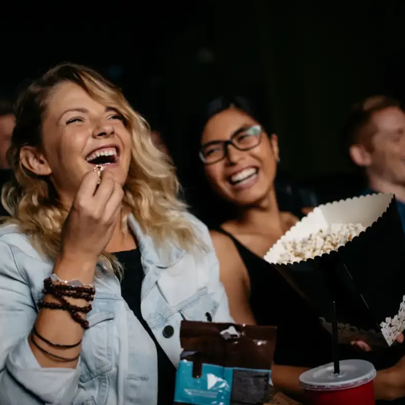 Young woman with friends watching movie in cinema and laughing