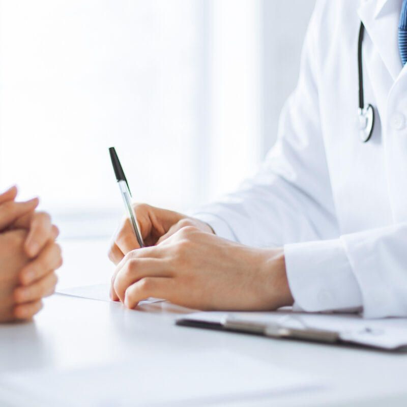 Close Up Of Patient And Doctor Taking Notes